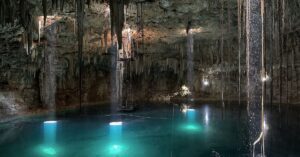 Crystal-clear cenote near Mérida with sunlight streaming into turquoise water and swimmers enjoying the natural cave